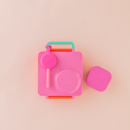 Pink and green container with a lid on a pink background