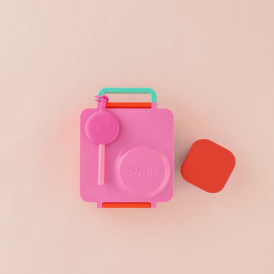 Pink lunchbox with a red container on a beige background