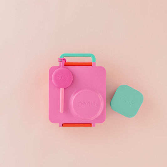Pink lunchbox with a green container on a pink background