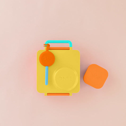Yellow lunch box with colorful handles on a pink background