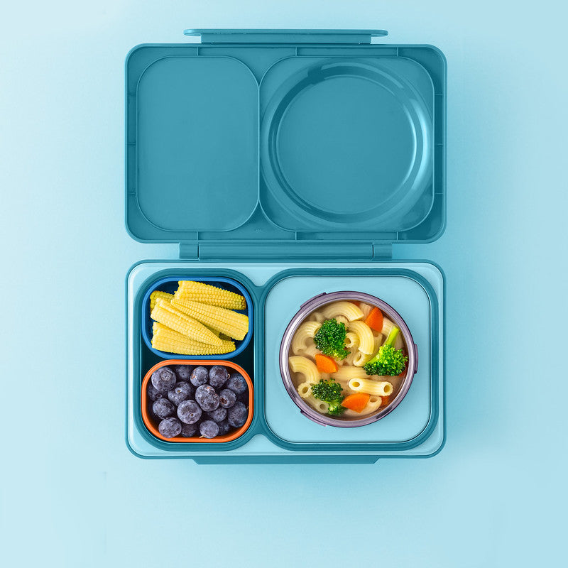 Blue bento box with compartments containing food on a light blue background