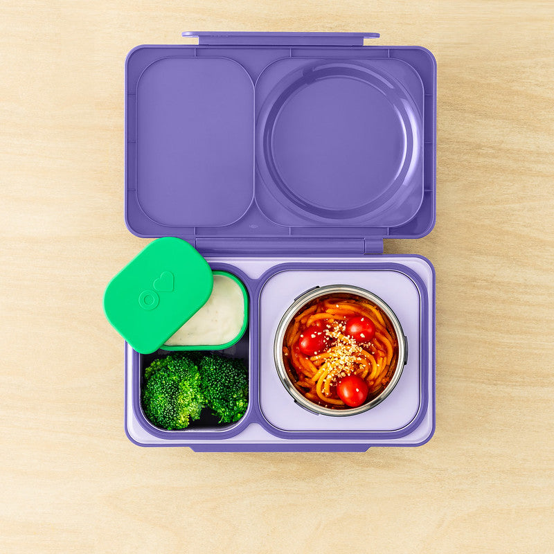 Purple bento box with compartments containing food on a wooden surface