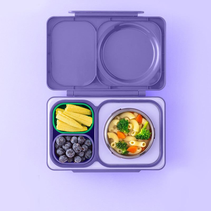 Purple bento box with compartments containing food on a purple background