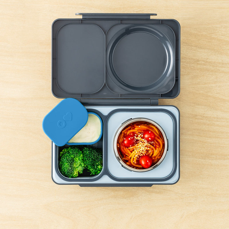 Open lunch box with compartments containing food on a wooden surface