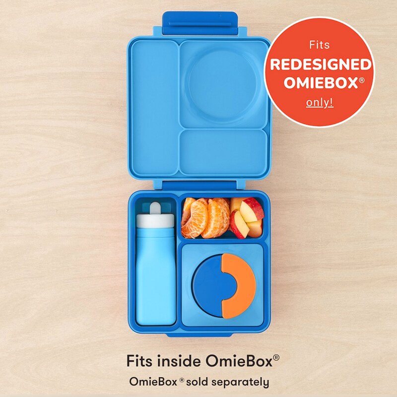 Blue bento box with compartments containing food items on a beige background, with a red circle indicating compatibility with Redesigned OmieBox.