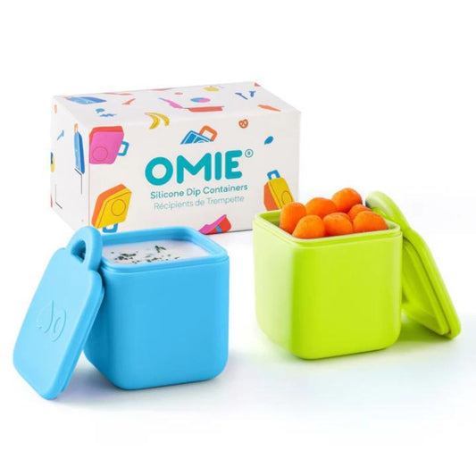 Two silicone dip pots, one blue and one green, with their packaging box. The pots are designed for use with an OmieBox lunchbox.