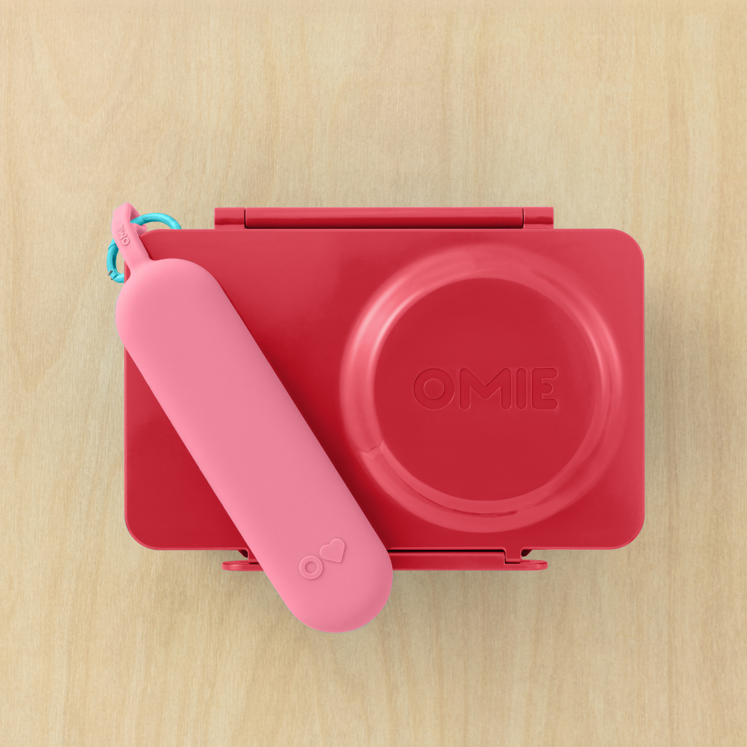 Red and pink baby bottle sterilizer with 'OMIE' branding on a wooden surface