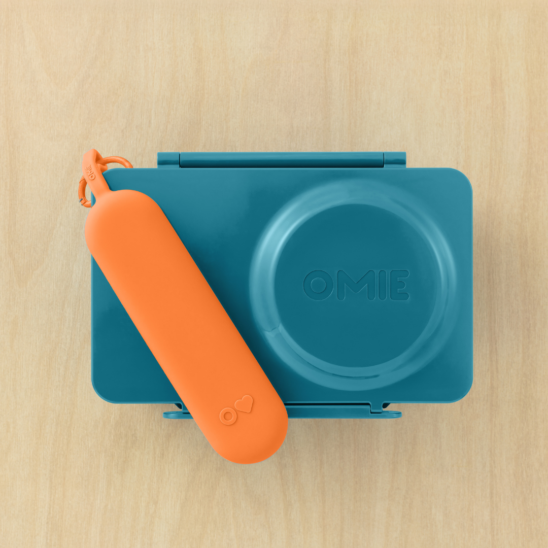 Blue and orange container with a lid on a wooden surface, featuring the brand 'OMIE'.