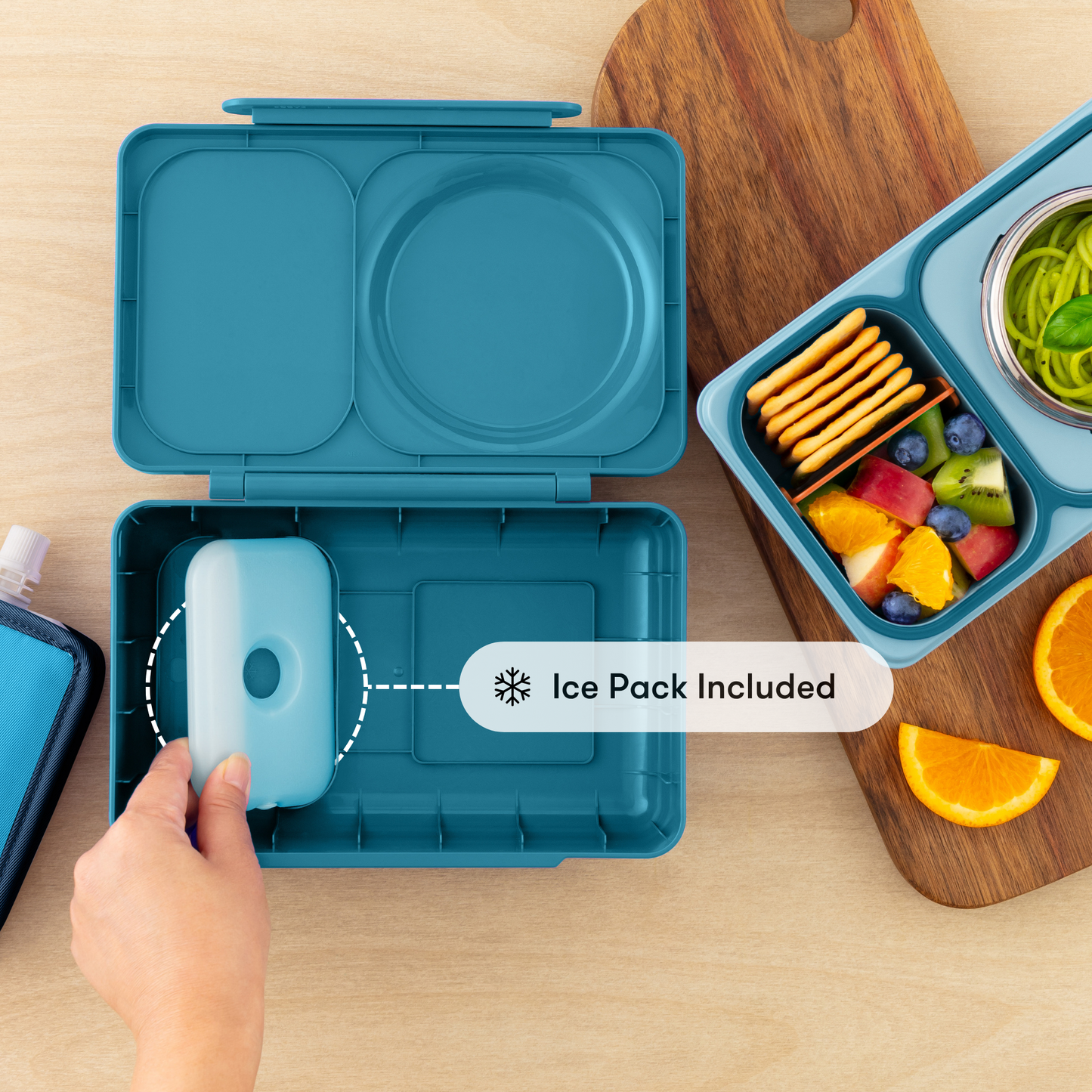 Blue bento box with ice pack included, shown on a wooden surface with food items.