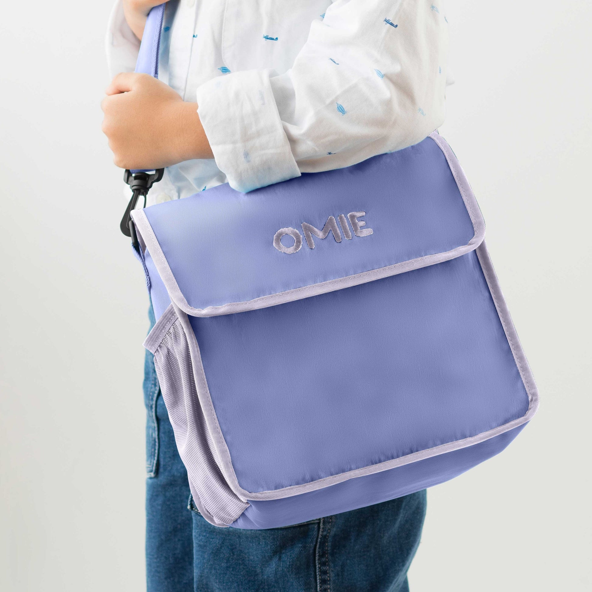 Person holding a purple bag with 'OMIE' branding on a white background