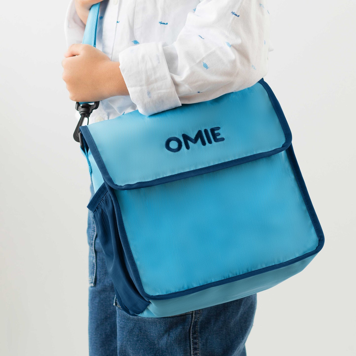Person holding a blue bag with 'OMIE' branding on a white background