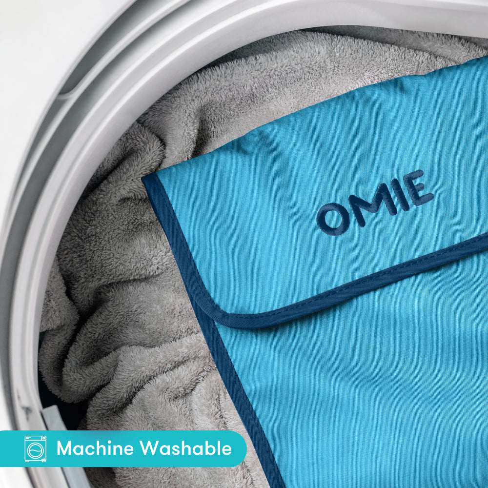 Blue towel with 'OMIE' branding inside a washing machine.