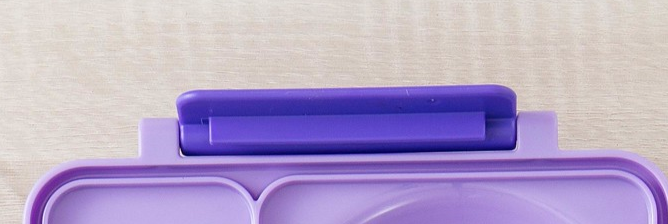 A blue replacement latch for the OmieBox food storage container.