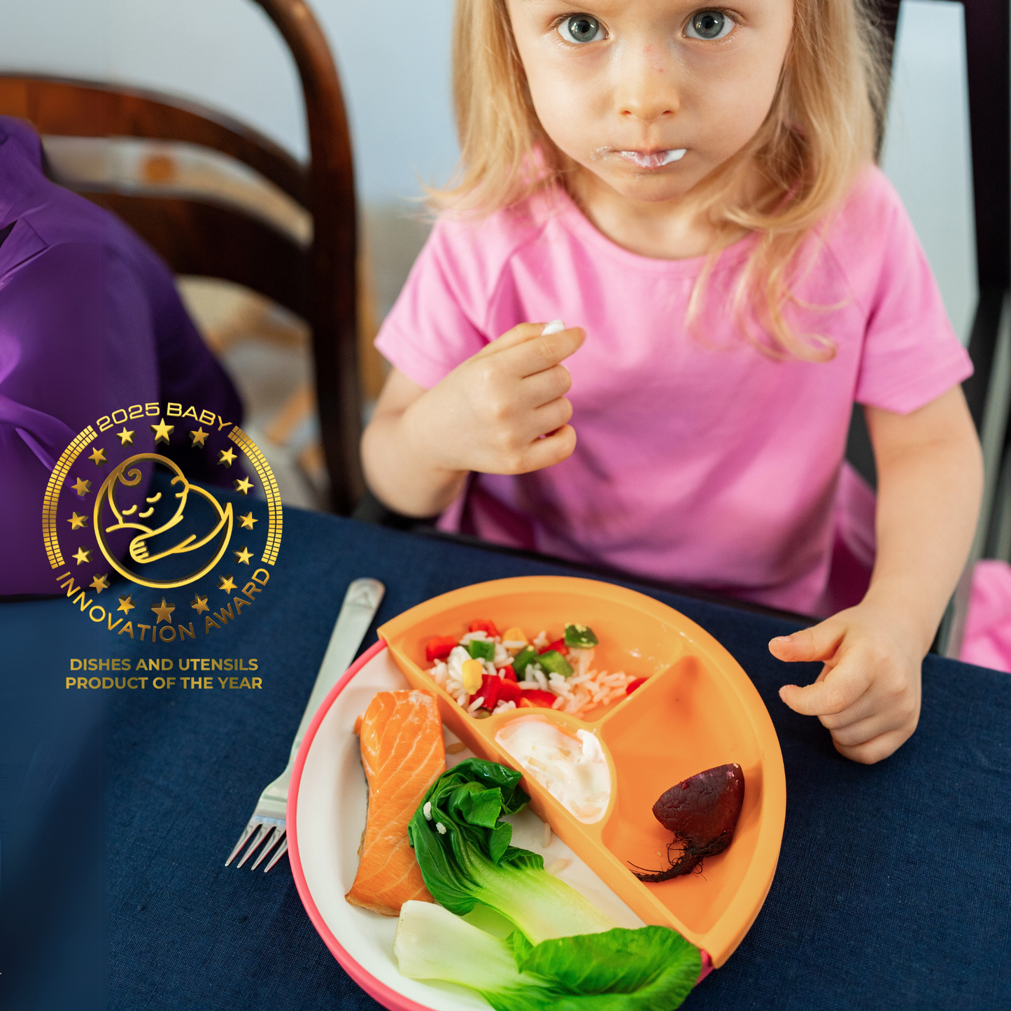 Child sitting at a table with a colorful plate of food, holding a fork, and an award logo for 'Product of the Year' displayed.